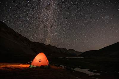 Tent at night in the ountains under a starry sky.