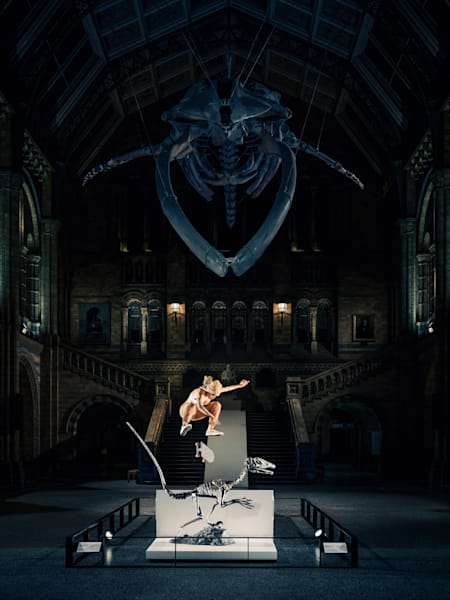 A skatista brasileira Leticia Bufoni dando um kickflipping sobre um esqueleto de dinossauro velociraptor no salão principal do Museu de História Natural de Londres, em abril de 2023.