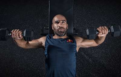 Le pilote de motocross Mohammed Jaffar fait des développés couchés avec des haltères lors d'un entraînement,