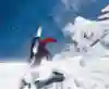 A photograph of American snowboarder Jeremy Jones trekking in the snow with splitboards strapped to his back.