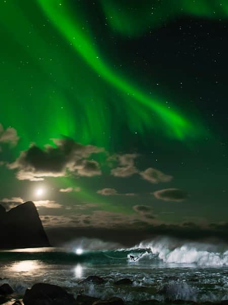 Surfer Mick Fanning surfing at night under the Northern Lights in Narvik, Norway