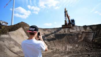 Surveying the Red Bull Dirt Diggers event site, with a digger and large wind turbine in view.