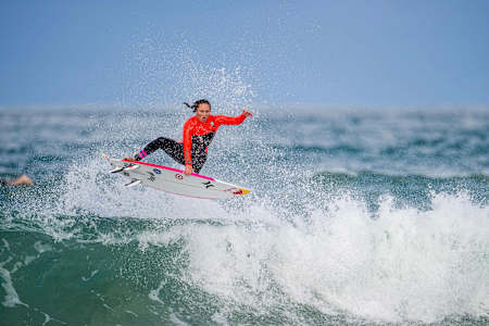 La surfeuse Carissa Moore exécute un impressionnant aerial au-dessus d'une vague lors d'une session de surf.