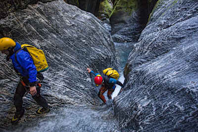 Two canyon particpants walk up a canyon wall in Wanaka, New Zealand.