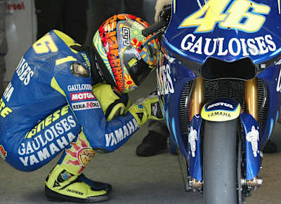 Valentino Rossi se agacha al lado de la Yamaha M1