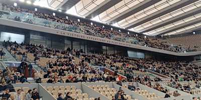 Les spectateurs prennent place sous les aile du toit du court Philippe-Chatrier à Roland-Garos.
