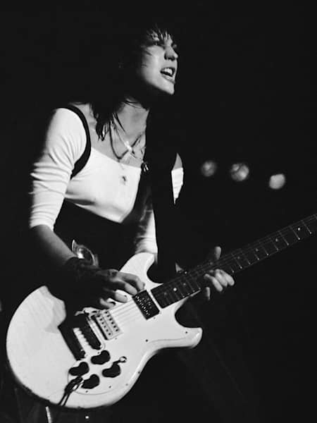 A black and white photo of Joan Jett performing live.