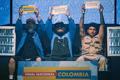 En 2026, tres artistas levantan carteles de Marithea en el escenario de la Final Nacional de Red Bull de Colombia, en Bogotá, con latas de Red Bull como telón de fondo de la celebración