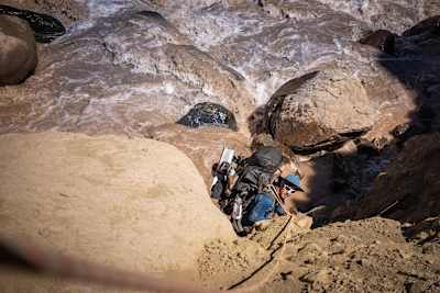 Man looks up from ravine next to riverin the Andes.