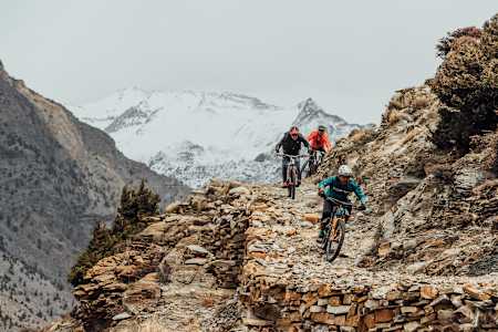 A group of mountain bikers ride through rocky terrain in the Himalayas in Nepal.