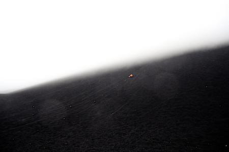 Person in orange rides down an ash slope in Nicaragua.