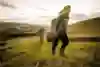 Two people walk up a hill carrying camping kit.