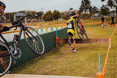 Un competidor carga con su bici para saltar una tabla en una carrera de ciclocross en Brasil.