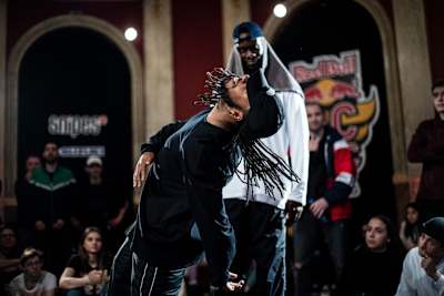 A dancer doing a freestyle dance while his partner watches in the background.