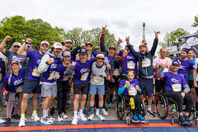 Teilnehmer, Rollstuhlfahrer und Athleten posieren beim Wings for life World Run in München 2022 für ein Jubelfoto.