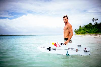 Surf-Profi Leon Glatzer geht bei einem Surf-Trip auf den Malediven mit seinem Suerfbrett ins Wasser.