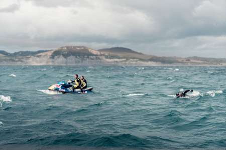 Ross Edgely is joined by a jetski as he swims in choppy waters off Weymouth.