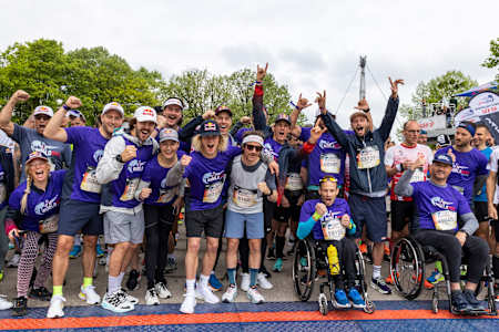 Teilnehmer, Rollstuhlfahrer und Athleten posieren beim Wings for life World Run in München 2022 für ein Jubelfoto.
