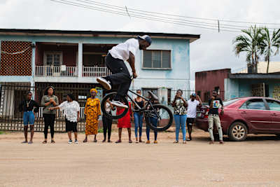 Courage Adams rides his BMX in front of members of his extended family in Benin City, Nigeria on April 30, 2019.