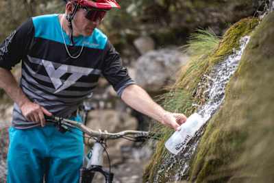Rob Warner collects spring water into his riding bottle during a trail tide on the Old Ghost Road in the Buller District of New Zealand.