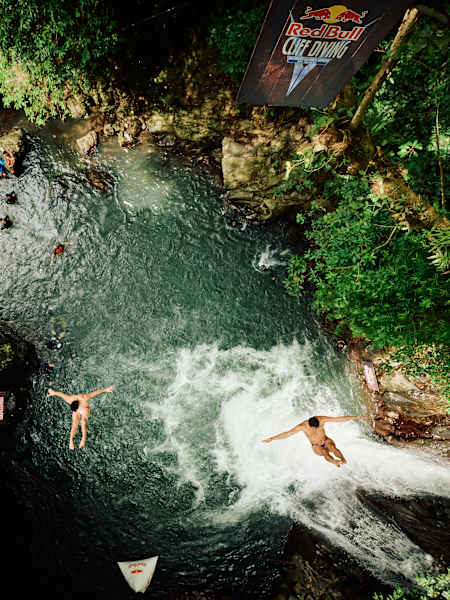 Aidan Heslop and Jonathan Paredes dive from a tree at Kroya Waterfall in Bali during Red Bull Cliff Diving World Series 2026, showcasing fearless athleticism amid stunning tropical scenery