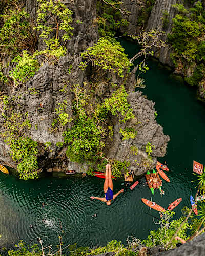 Rhiannan Iffland dives off a steep cliff, surrounded by lush vegetation