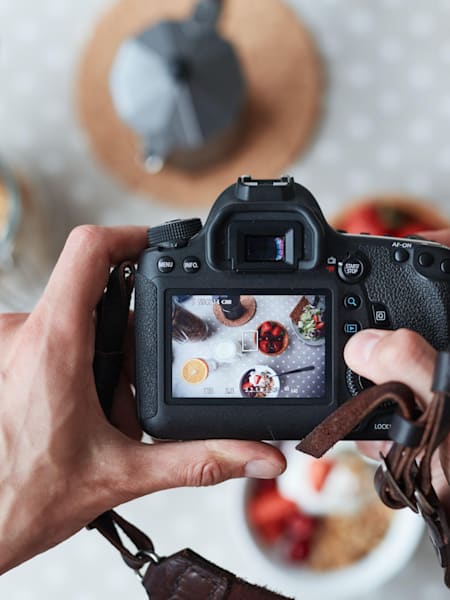 A photo of a photographer using a camera to take an image of food.