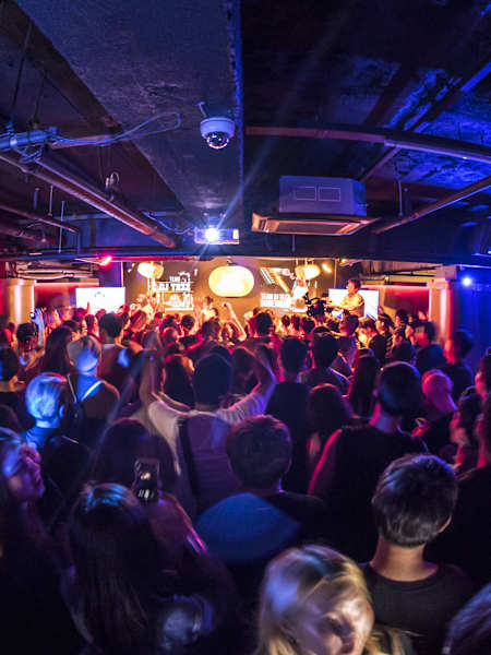 A crowd dances to a DJ in a Seoul club.