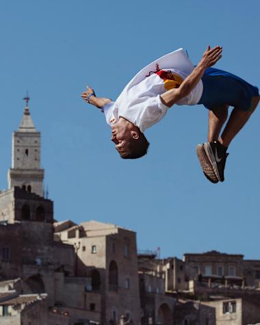 A freerunner pictured mid-air with a backdrop of a town behind.