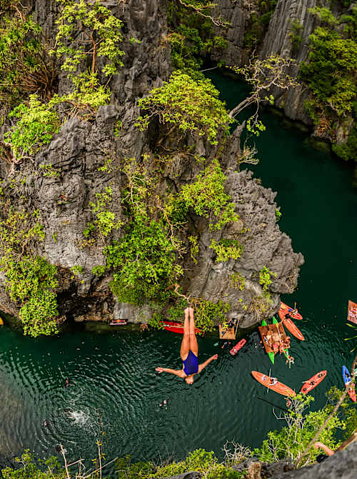Rhiannan Iffland dives off a steep cliff, surrounded by lush vegetation