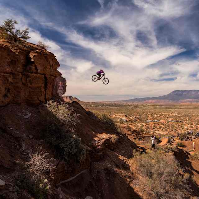 Chelsea Kimball soars off a cliff edge on her mountain bike during the women's final at the extreme Red Bull Rampage freeride event in the rugged Utah desert landscape, 2024