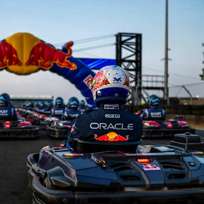 Red Bull Racing competitors line up for Max vs 100 at Silverstone, Great Britain, on 22 July 2026, with Max Verstappen’s kart and helmet leading the field beneath the Red Bull arch