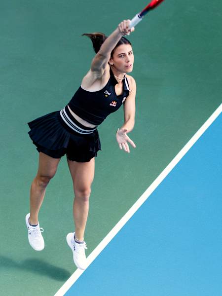 Emma Navarro führt ihren Aufschlag während eines Matches auf Hartplatz aus, konzentriert und in voller Streckung ihrer Bewegung.