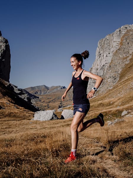 woman downhill running a mountain with a smile on her face