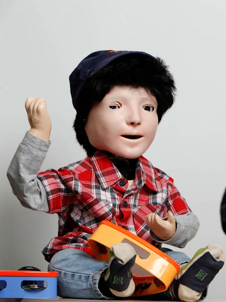 An child interacts with Kaspar, the social robot built to help autistic children learn social skills.