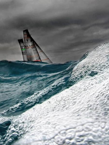 A sailing boad fighting agains the rouch sea and the waves at the America's Cup Final.
