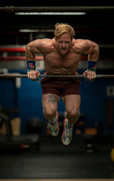 Functional fitness pro Noah Ohlsen mid‑rep on a bar during training.