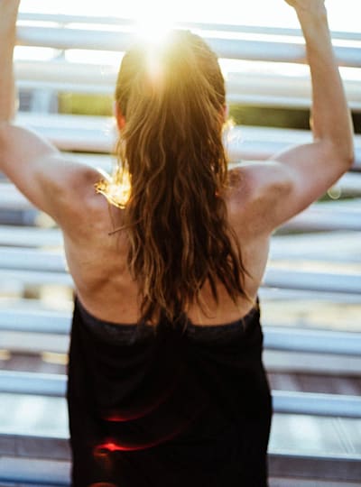 Woman in vest top doing a pull up.