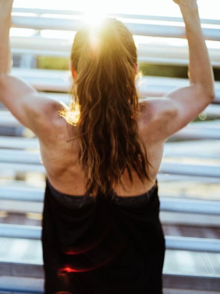 Woman in vest top doing a pull up.