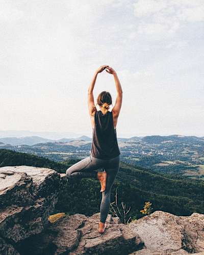 Woman does yoga on top of a mountain.
