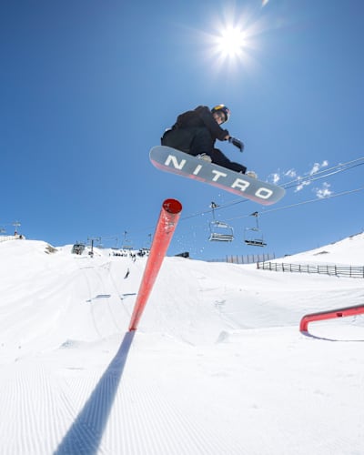 Cool Wakushima jumps from a rail feature in the snowboard park at Cardrona Alpine resort near Wanaka, New Zealand in October 2025 