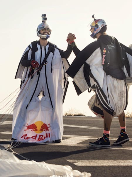 Dos wingsuit flyers se saludan tras completar un vuelo.