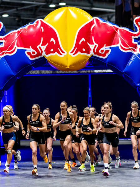 Een groep vrouwelijke atleten rent door een opblaasbare Red Bull boog tijdens de HYROX Major in Hong Kong in november 2024.