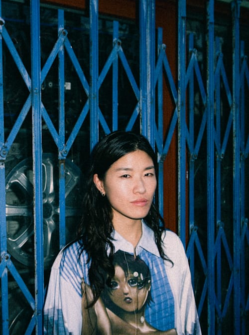 DJ Jennifer Loveless poses in front of a gate-