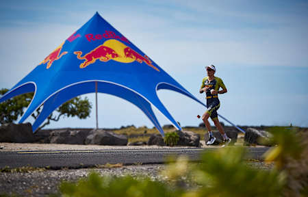 Sebastian Kienle läuft während des IRONMAN an einer Energy Station vorbei.