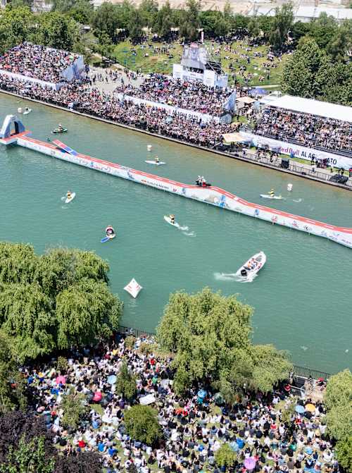 Súťažiaci pretekajú na vynaliezavých vodných plavidlách na Red Bull Al Agua Pato 2025 v Parque de la Familia v Santiagu v Čile, zatiaľ čo nadšené davy povzbudzujú na brehu rieky.