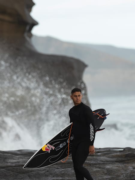 Kehu Butler marche avec sa planche de surf pendant le Red Bull Pro à Muriwai Beach, Auckland, Nouvelle-Zélande, le 21 mai 2021.