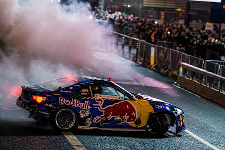 Bild zeigt das Auto von Conor Shanahan beim Red Bull Showrun in Dublin, Irland beim Driften mit Rauch und Zuschauern im Hintergrund.