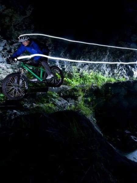 Night riding in a forest with a light trail.