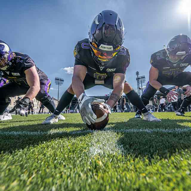 Five Vienna Vikings players crouch in a scrimmage line, one holding the ball